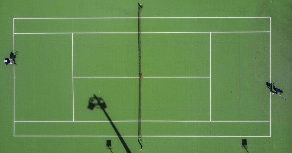 Top view of a green tennis course with a player either end