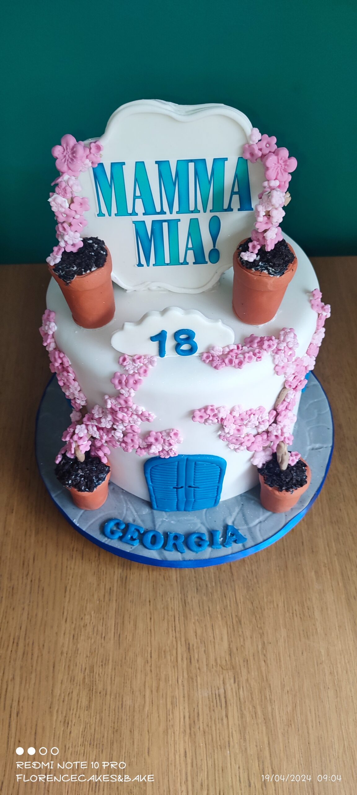 Mamma Mia Cake with a blue door and flower pots with crawling flowers over the cake